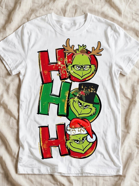 Бяла тениска с Grinch HO HO HO — три лица с рога, цилиндър и коледна шапка